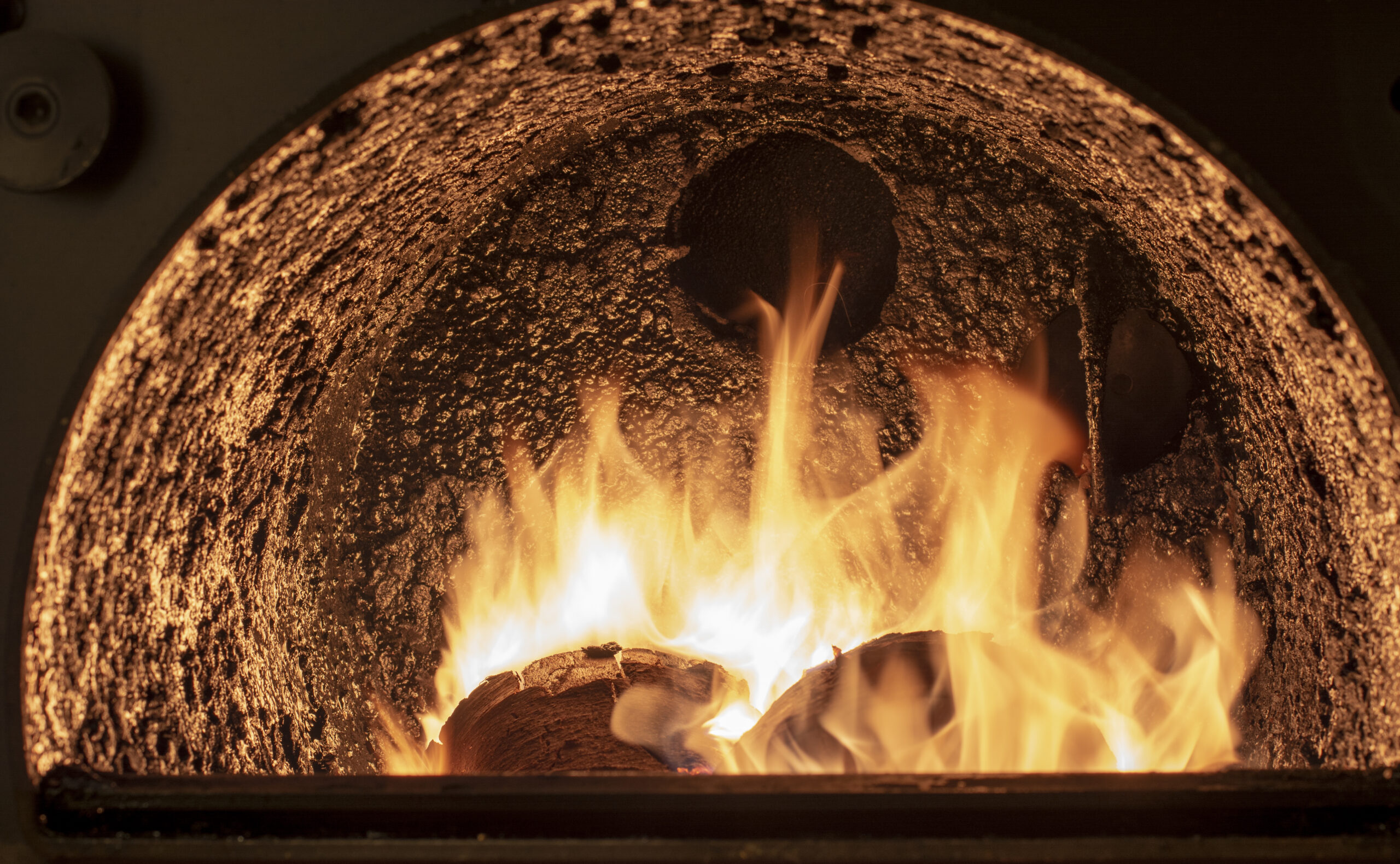 Tar deposit inside the wood fuel boiler. Shinny black deposit inside the solid fuel boiler. Creosote deposit.